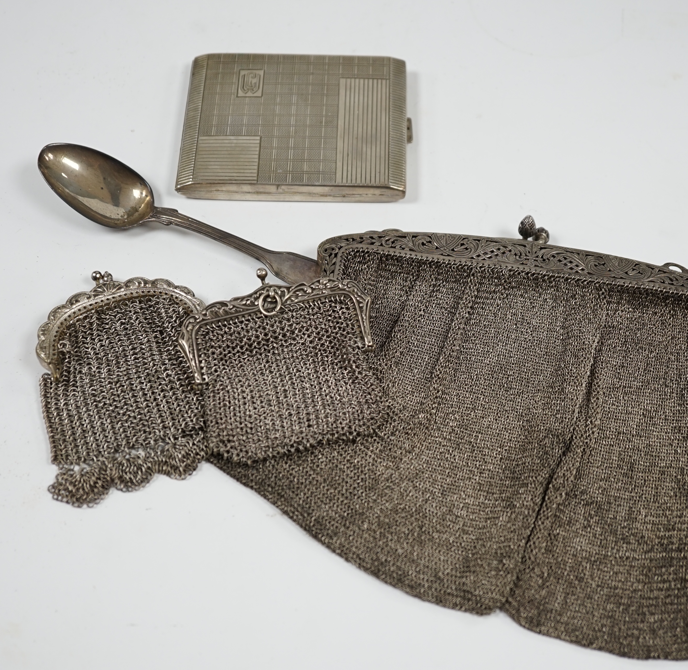 An Art Deco German? 800 standard white metal cigarette case, a white metal mesh evening bag and two similar purses and a Victorian silver fiddle and thread pattern teaspoon. Condition - poor to fair